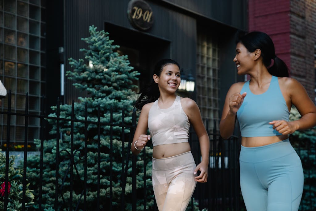 Smiling women jogging together in fashionable sports clothes, showcasing health and lifestyle.